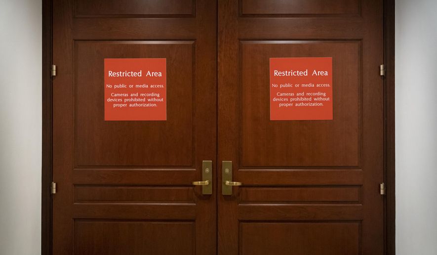 In this Nov. 6, 2019, photo, bright red signs alert non-authorized personnel at the entrance to the House SCIF, the Sensitive Compartmented Information Facility, located three levels beneath the Capitol where witnesses and lawmakers hold closed interviews in the impeachment inquiry on President Donald Trump's efforts to press Ukraine to investigate his political rivals, in Washington. (AP Photo/J. Scott Applewhite)