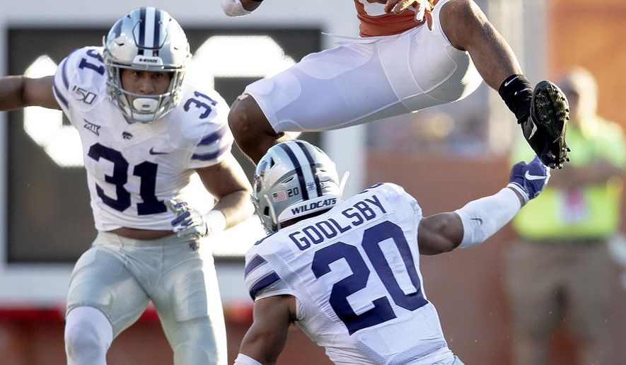 Texas running back Roschon Johnson (2) hurdles Kansas State defensive back Denzel Goolsby (20) during an NCAA college football game Saturday, Nov. 9, 2019, in Austin, Texas. (Nick Wagner/Austin American-Statesman via AP)