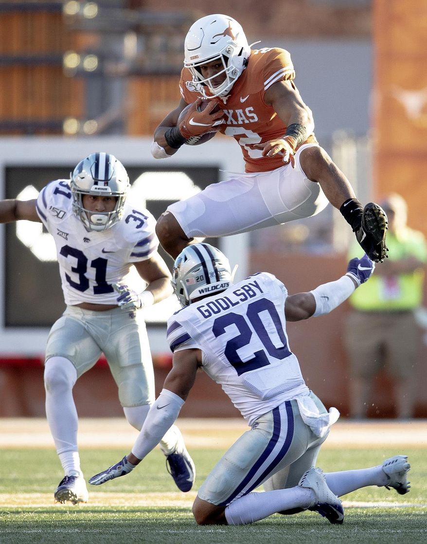 Texas running back Roschon Johnson (2) hurdles Kansas State defensive back Denzel Goolsby (20) during an NCAA college football game Saturday, Nov. 9, 2019, in Austin, Texas. (Nick Wagner/Austin American-Statesman via AP)