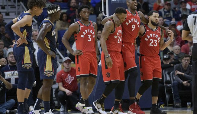 Toronto Raptors forward Serge Ibaka (9) leaves the court with the help of guard Fred VanVleet (23) and guard Norman Powell (24) as New Orleans Pelicans guard Jrue Holiday (11) and center Jaxson Hayes (10) watch during the first half of an NBA basketball game in New Orleans, Friday, Nov. 8, 2019. (AP Photo/Matthew Hinton)