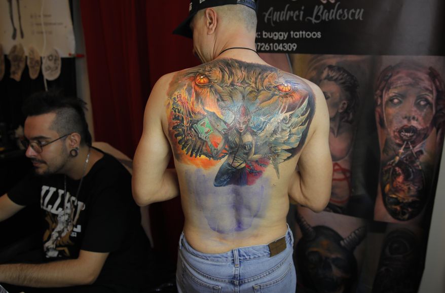 In this Saturday, Nov. 2, 2019, a man waits for ink to dry on a tattoo he's getting on his back during the 10th International Tattoo Convention in Bucharest, Romania. (AP Photo/Vadim Ghirda)