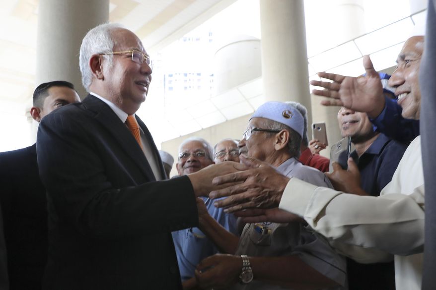 Former Malaysian Prime Minister Najib Razak, left, greets supporters as he arrives at Kuala Lumpur High Court in Kuala Lumpur, Malaysia, Monday, Nov. 11, 2019. An important court ruling Monday in the first corruption trial of Najib will be a test of the legal system and of the credibility of the prime minister who brought about his shocking ouster from office last year. (AP Photo/Vincent Thian)