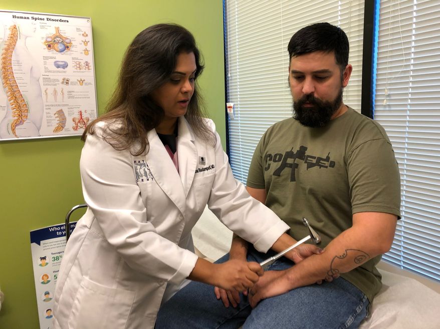 Iraq War veteran Zachary Muñoz (right) receives a free checkup from Dr. Suneetha Budampati, executive physician for National Spine and Pain Centers in Arlington, Virginia, on Monday. Mr. Muñoz lives with chronic back pain and incurred a traumatic brain injury when a bomb set off under his military vehicle in 2007. (Shen Wu Tan/ The Washington Times)
