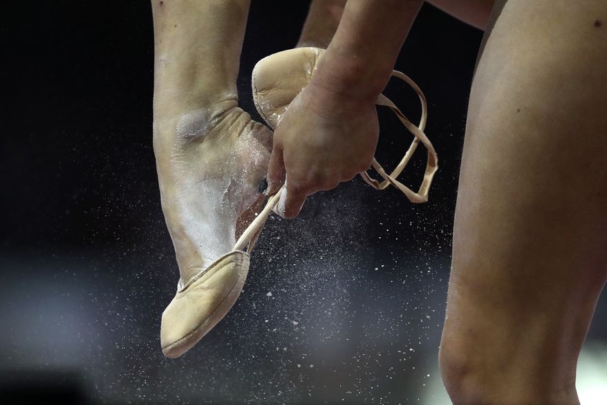 Diana Varinska of Ukraine puts on her shoes to perform on the floor in the women's all-around final at the Gymnastics World Championships in Stuttgart, Germany, Thursday, Oct. 10, 2019. (AP Photo/Matthias Schrader)