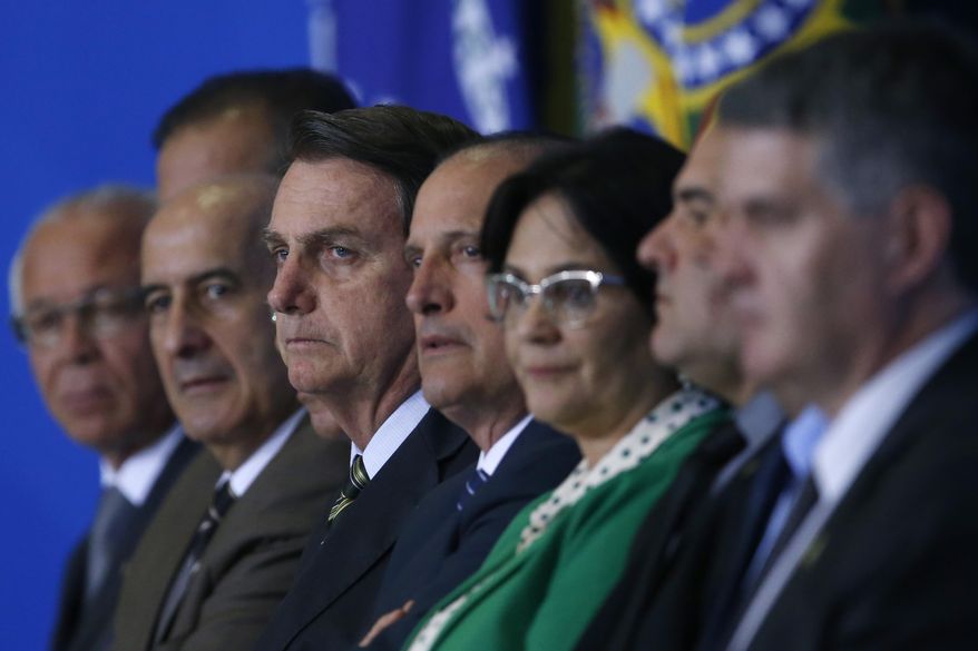 Brazil's President Jair Bolsonaro, center, and his ministers attend the launch of the Green and Yellow program to create formal jobs for young people, at the Planalto Presidential Palace, in Brasilia, Brazil, Monday, Nov. 11, 2019. (AP Photo/Eraldo Peres)