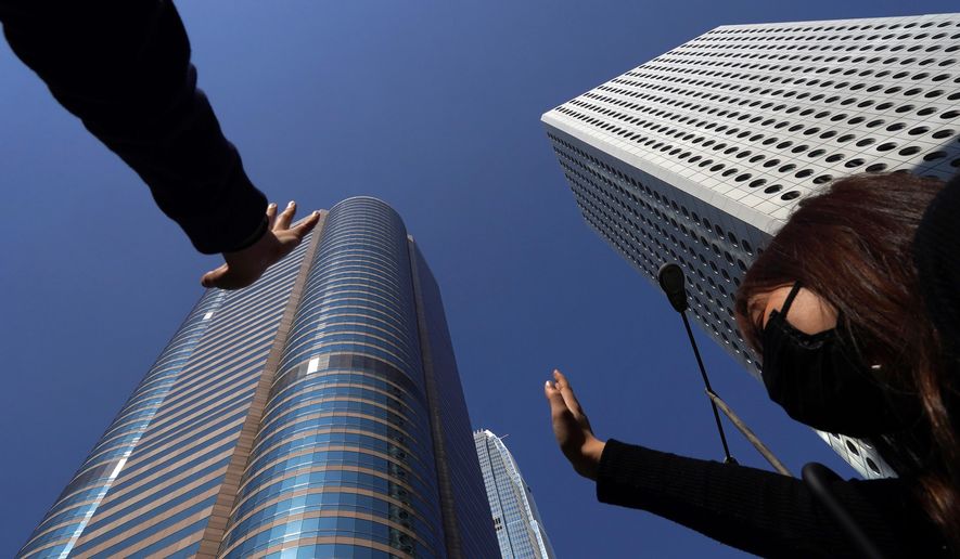 Protesters hold up their hands to represent their five demands in Hong Kong on Monday, Nov. 11, 2019. A protester was shot by police Monday in a dramatic scene caught on video as anti-government demonstrators blocked train lines and roads during the morning commute. (AP Photo/Vincent Yu)