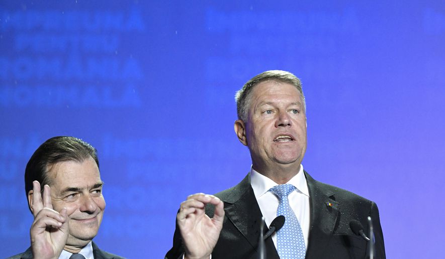 Romanian President Klaus Iohannis, right, speaks next to Romanian Prime Minister Ludovic Orban, after exit polls results indicate him as the leader of the presidential race, with up to 40 percent of the votes in Bucharest, Romania, Sunday, Nov. 10, 2019. An election runoff will take place on Nov. 24. (AP Photo/Andreea Alexandru)