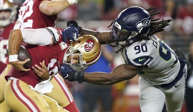San Francisco 49ers quarterback Jimmy Garoppolo, left, avoids being sacked by Seattle Seahawks defensive end Jadeveon Clowney (90) during the second half of an NFL football game in Santa Clara, Calif., Monday, Nov. 11, 2019. (AP Photo/Tony Avelar)