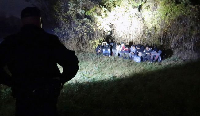 In this photo taken Saturday, Nov. 9, 2019, Bosnian border police officers guard migrants after making the illegal crossing from Serbia by the Drina river, the natural border between Bosnia and Serbia, near eastern Bosnian town of Zvornik, Bosnia. Bosnian border police are warning they cannot contain migratory pressures along the country&#x27;s eastern border with Serbia, warning the situation could easily escalate and put in danger the overall stability of their politically fragile nation. (AP Photo/Eldar Emric)
