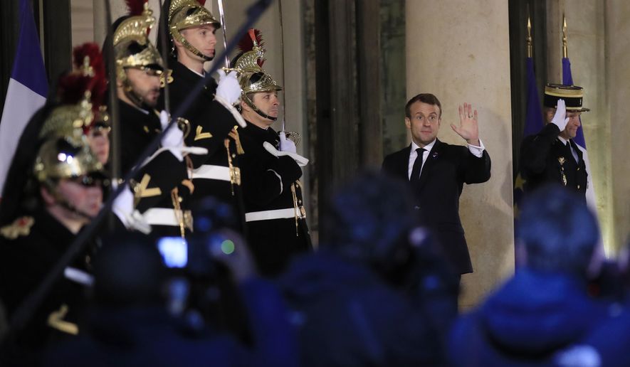 French President Emmanuel Macron waves to the media as he walks in to the the Elysee Palace in Paris, Monday, Nov. 11, 2019, to host. Head of States and officials gathering in Paris for the Peace Forum which starts tomorrow Nov. 12, 2019. (AP Photo/Michel Euler)