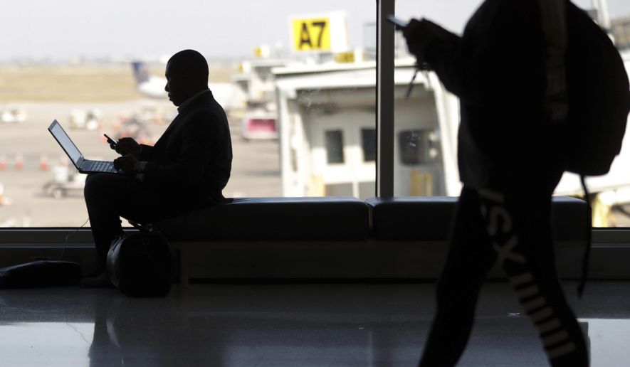FILE - In this Wednesday, Nov. 21, 2018 file photo, travelers check their phones at Indianapolis International Airport in Indianapolis. On Tuesday, Nov. 12, 2019, a federal court in Boston ruled that warrantless U.S. government searches of the phones and laptops of international travelers at airports and other U.S. ports of entry violate the Fourth Amendment. (AP Photo/Michael Conroy)
