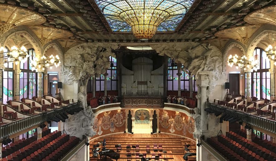 This Oct. 14, 2019 photo shows the inside of Palau de la Música Catalana, built by famed architect Lluís Domènech I Montaner,  in Barcelona, Spain. A required tour of the music hall’s crescendo of colorful stained glass and mosaics is pricey but worth it, and you may even catch musicians practicing. (Courtney Bonnell via AP)