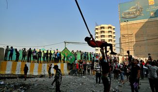 An anti-government protester swings from a cable during ongoing demonstrations, in Baghdad, Iraq, Wednesday, Nov. 13, 2019. Protesters say an intensifying crackdown by Iraqi authorities is instilling fears but remain defiant with calls for millions to return to the streets this week. (AP Photo/Hadi Mizban)