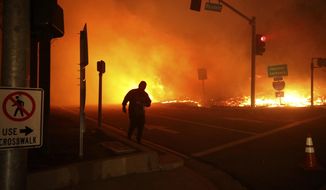 FILE - In this Oct. 11, 2019 file photo, a bystander watches the Saddleridge Fire in Sylmar, Calif. California regulators are voting Wednesday, Nov. 13, on whether to open an investigation into pre-emptive power outages that blacked out large parts of the state for much of October as strong winds sparked fears of wildfires. Pacific Gas &amp;amp; Electric Co. officials insisted on the shut-offs to prevent wildfires but a parade of public officials complained the company botched its communications. (AP Photo/David Swanson, File)