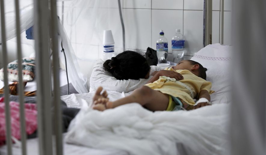 In this Aug. 20, 2019 file photo, a relative embraces a young patient receiving treatment for dengue at the University School Hospital in Tegucigalpa, Honduras. In an international report released on Wednesday, Nov. 13, 2019, doctors say children are growing up in a warmer world that will hit them with more and different health problems than their parents had. (AP Photo/Eduardo Verdugo)