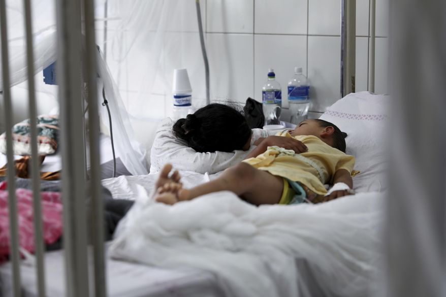 In this Aug. 20, 2019 file photo, a relative embraces a young patient receiving treatment for dengue at the University School Hospital in Tegucigalpa, Honduras. In an international report released on Wednesday, Nov. 13, 2019, doctors say children are growing up in a warmer world that will hit them with more and different health problems than their parents had. (AP Photo/Eduardo Verdugo)