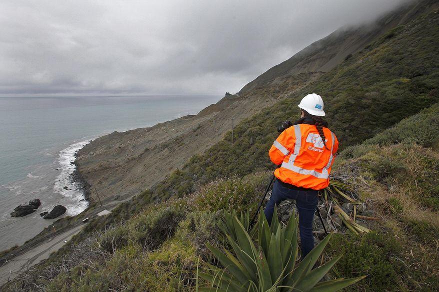 File - In this May 25, 2017, file photo, Cal Trans public affairs officer Jessica Biro photographs the southern end of the Mud Creek slide as it covers Highway One in southern Monterey County on the coast in Big Sur, Calif. The California Department of Transportation plans to temporarily close landslide-plagued Highway 1 on the southern Big Sur coast when there are forecasts of significant rains this winter. The Monterey Herald reports Caltrans will notify the public 48 hours before any potential closures, which would take place at Mud Creek or Paul's Slide. (Vern Fisher/The Monterey County Herald via AP, File)