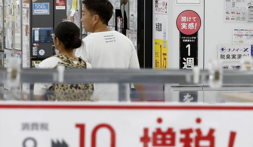 FILE - In this Sept. 30, 2019, file photo, a signboard says "Consumption tax hike, 8 percent to 10 percent", at a mass home electronics retailer in Tokyo. Japan reports on Thursday, Nov. 14, 2019 its economy grew at an annual pace of 0.2% in July-September, supported by consumer purchases ahead of a tax hike. (Shinji Kita/Kyodo News via AP, File)