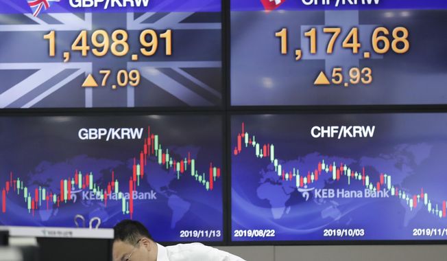 A currency trader works near the screens showing the foreign exchange rates at the foreign exchange dealing room in Seoul, South Korea, Wednesday, Nov. 13, 2019. Asian stocks sank Wednesday after U.S. President Donald Trump threatened more tariff hikes on Chinese imports if talks aimed at ending a trade war fail to produce an interim agreement. (AP Photo/Lee Jin-man)