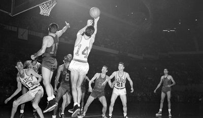 Bob Cousy (14) of the Boston Celtics takes a rebound off the backboard after an attempted basket by Dick McGuire (15) of the New York Knickerbockers in the fourth quarter of their NBA playoff game at the Boston Garden in Boston, Mass., March 26, 1953. Other identifiable players are: Bob Harris (13) and Bill Sharman (21) of the Celtics: Nat Clifton (8) and Ernie Vandeweghe (9) both of the Knicks. The Celtics won 86-70. (AP Photo/Bill Chaplis)