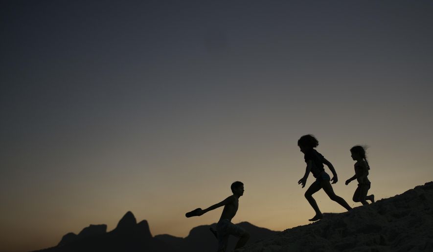 FILE - In this Aug. 1, 2016 file photo, children are silhouetted against the setting sun as they run on the sand at Ipanema beach in Rio de Janeiro, Brazil. Homeland Security investigators who uncover child exploitation initiated more than 4,000 cases around the world in 2019. Data obtained by The Associated Press shows the investigations resulted in thousands of arrests and the identification of more than 1,000 victims. On Thursday, Nov. 14, 2019, officials plan to unveil a new center based at Immigration and Customs Enforcement’s headquarters in Washington tasked with alerting other countries when U.S. sex offenders are traveling there. (AP Photo/Felipe Dana, File)