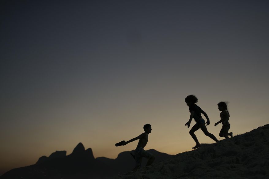 FILE - In this Aug. 1, 2016 file photo, children are silhouetted against the setting sun as they run on the sand at Ipanema beach in Rio de Janeiro, Brazil. Homeland Security investigators who uncover child exploitation initiated more than 4,000 cases around the world in 2019. Data obtained by The Associated Press shows the investigations resulted in thousands of arrests and the identification of more than 1,000 victims. On Thursday, Nov. 14, 2019, officials plan to unveil a new center based at Immigration and Customs Enforcement’s headquarters in Washington tasked with alerting other countries when U.S. sex offenders are traveling there. (AP Photo/Felipe Dana, File)