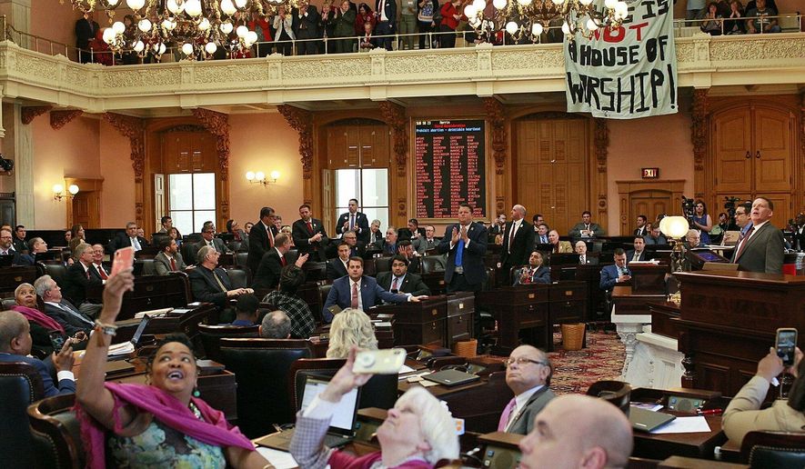 FILE - In this April 10, 2019 file photo, some members of the Ohio House applaud following their vote while others photograph protestors who unfurled banners reading "This is not a House of Worship" and "This is not a Doctor's office" following a vote on the Heartbeat Bill at the Ohio Statehouse in Columbus, Ohio. A group of conservative lawmakers in Ohio has introduced a bill to outlaw abortion outright, declaring a fetus a person and subjecting doctors who terminate pregnancies to potential murder charges. The legislation introduced Thursday, Nov. 14, appears to make an exception for the life of the mother.(Brooke LaValley/The Columbus Dispatch via AP, File)