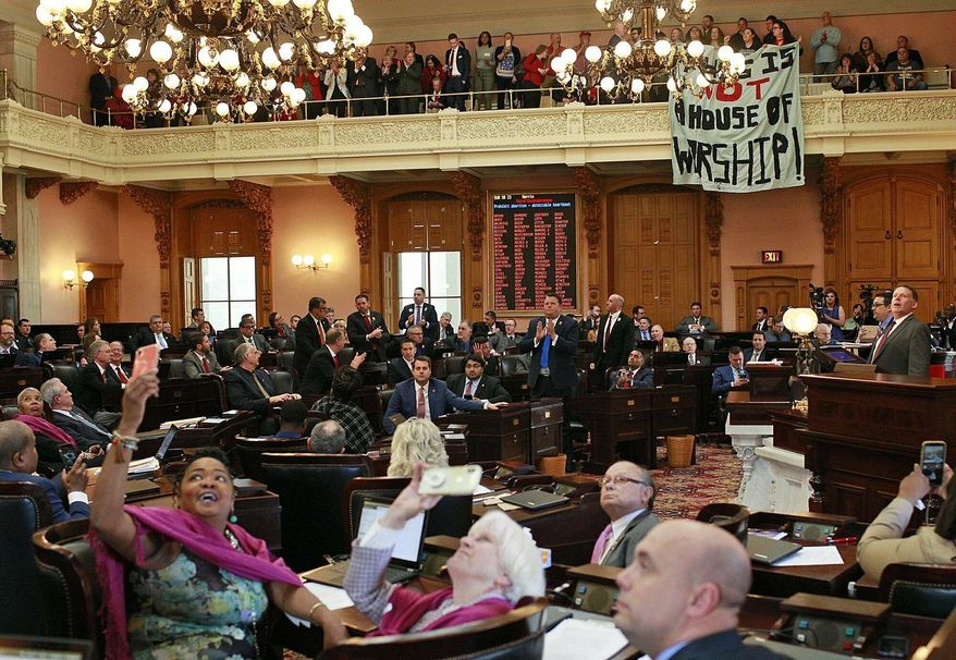 FILE - In this April 10, 2019 file photo, some members of the Ohio House applaud following their vote while others photograph protestors who unfurled banners reading "This is not a House of Worship" and "This is not a Doctor's office" following a vote on the Heartbeat Bill at the Ohio Statehouse in Columbus, Ohio. A group of conservative lawmakers in Ohio has introduced a bill to outlaw abortion outright, declaring a fetus a person and subjecting doctors who terminate pregnancies to potential murder charges. The legislation introduced Thursday, Nov. 14, appears to make an exception for the life of the mother.(Brooke LaValley/The Columbus Dispatch via AP, File)
