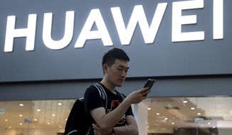 FILE - In this May 20, 2019, file photo, a man uses his smartphone outside a Huawei store in Beijing. Chinese tech giant Huawei is selling a folding smartphone without Google apps or U.S.-made processor chips following sanctions imposed by Washington. The Mate X went on sale Friday, Nov. 15, 2019 on Huawei’s online store in China priced at 16,999 yuan ($2,422) and competes with Samsung’s Galaxy Fold launched in September. (AP Photo/Ng Han Guan, File)