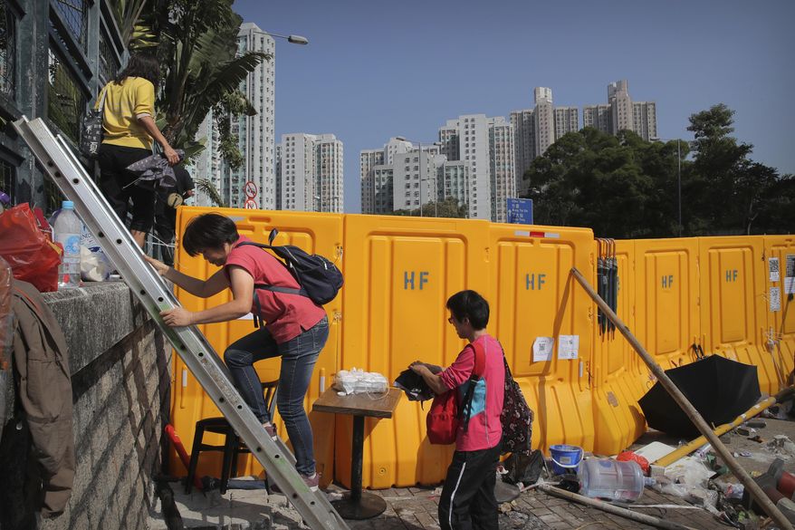 People use a ladder to climb around barricades built by protesters at Hong Kong Baptist University in Hong Kong, Friday, Nov. 15, 2019. Protesters who have barricaded themselves in a Hong Kong university partially cleared a road they were blocking and demanded that the government commit to holding local elections on Nov. 24. (AP Photo/Kin Cheung)