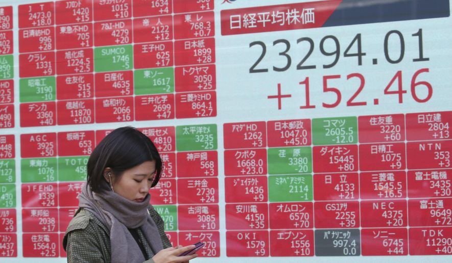 A woman walks by an electronic stock board of a securities firm in Tokyo, Friday, Nov. 15, 2019. Shares are higher in Asia after U.S. officials said China and the U.S. were getting close to an agreement to cool tensions over trade.(AP Photo/Koji Sasahara)