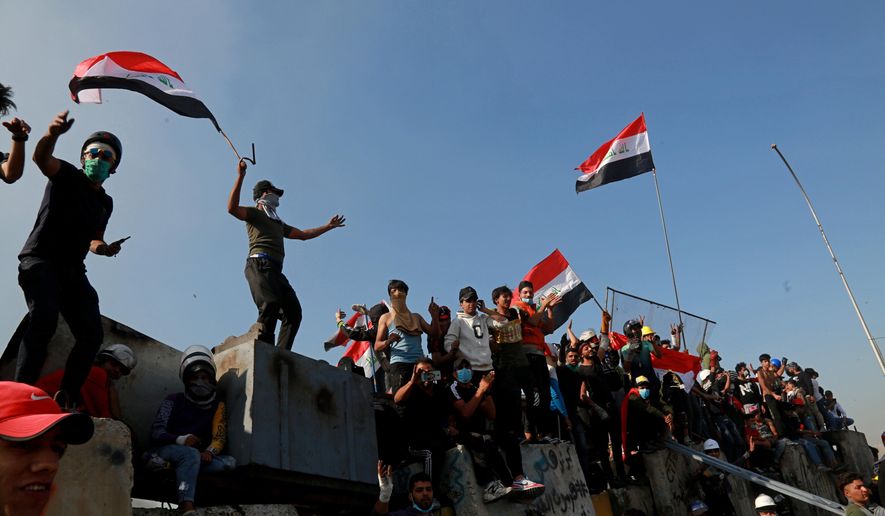 Protesters celebrate while taking control of some concrete walls and barriers set by security forces to close Sinak bridge leading to the Green Zone government areas during clashes between Iraqi security forces and anti-government demonstrators in Baghdad, Iraq, Saturday, Nov. 16, 2019.  Iraqi security and medical officials say protesters have pushed closer to the Green Zone, Baghdad’s fortified seat of government, after security forces pulled back following a night of violent altercations.(AP Photo/Khalid Mohammed)