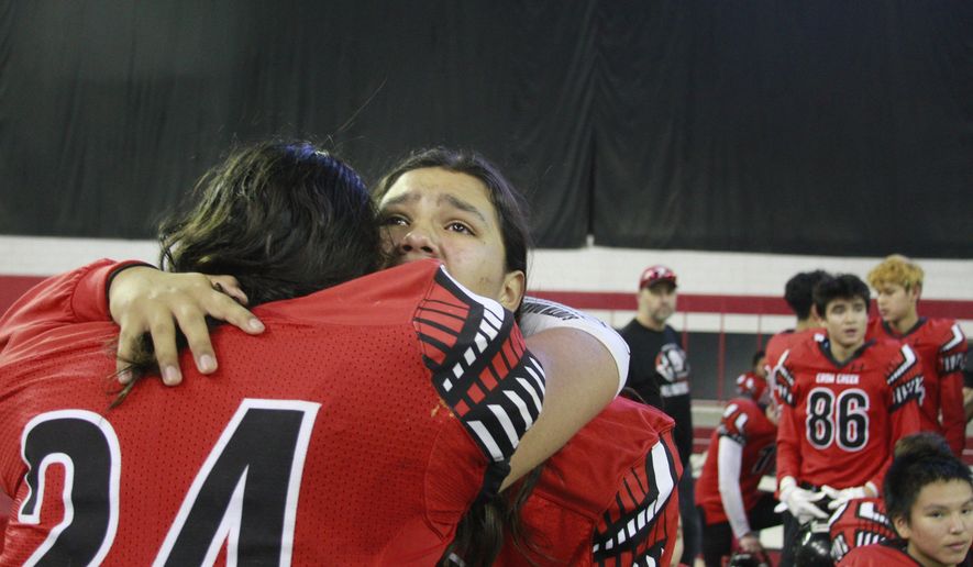 In this Nov. 8, 2019 photo, Jashawn Pease, right, embraces his brother Jayton, as they celebrate their 74-39 victory in the All Nations Football Conference championship in Vermillion, S.D. Jashawn and Jayton Pease shed tears as the Crow Creek Chieftains won the first All Nations Conference championship, and then remembered their older brother _ one of too many American Indians to die by suicide on a reservation with the highest suicide rate in South Dakota. (AP Photo/Stephen Groves)