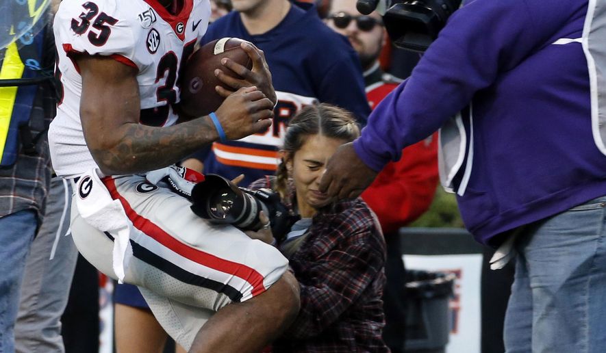Georgia running back Brian Herrien (35) runs out of bounds and into a photographer during the first half of an NCAA college football game against Auburn, Saturday, Nov. 16, 2019, in Auburn, Ala. (AP Photo/Butch Dill)