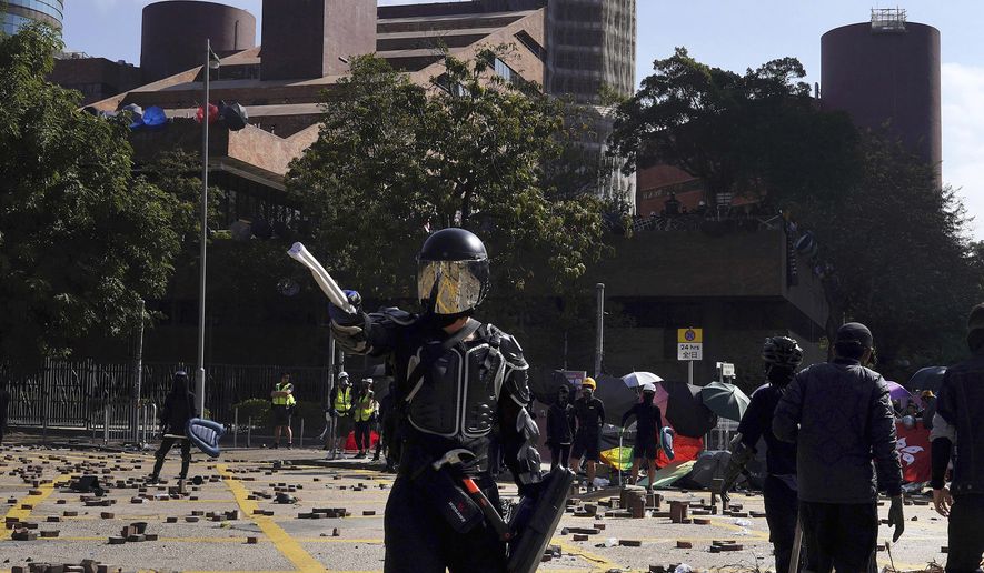 A protestor wearing a helmet and body armor gestures during unrest near Hong Kong Polytechnic University in Hong Kong, Sunday, Nov. 17, 2019. Police have fired tear gas at protesters holding out at Hong Kong Polytechnic University as overnight clashes resumed in the morning. (AP Photo/Vincent Yu)