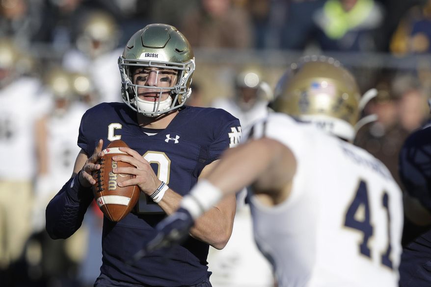 Notre Dame quarterback Ian Book (12) throws against Navy linebacker Tyler Pistorio (41) during the first half of an NCAA college football game, Saturday, Nov. 16, 2019, in South Bend, Ind. (AP Photo/Darron Cummings)