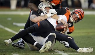 Cincinnati Bengals quarterback Ryan Finley, front, is sacked by Oakland Raiders defensive end Maxx Crosby during the second half of an NFL football game in Oakland, Calif., Sunday, Nov. 17, 2019. (AP Photo/Ben Margot)