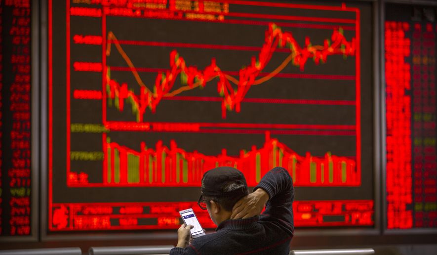 A Chinese investor uses his smartphone as he monitors stock prices at a brokerage house in Beijing, Tuesday, Nov. 19, 2019. Asian shares were mixed Tuesday as investor sentiment remained cautious amid worries about the next development in trade talks between the United States and China. (AP Photo/Mark Schiefelbein)