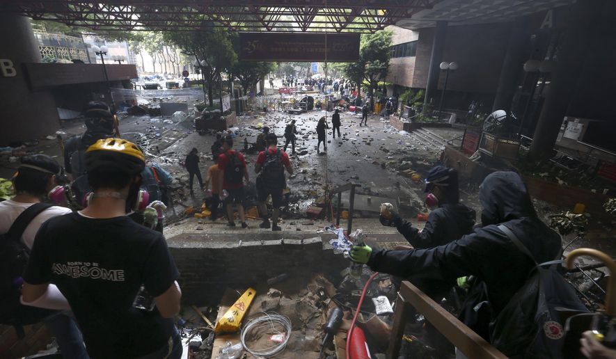 Protesters stand on the steps of the Hong Kong Polytechnic University in Hong Kong, Monday, Nov. 18, 2019. Hong Kong police have swooped in with tear gas and batons as protesters who have taken over the university campus make an apparent last-ditch effort to escape arrest. (AP Photo/Achmad Ibrahim)
