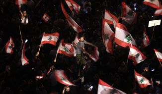 FILE - In this Oct. 21, 2019 file photo, anti-government protesters wave Lebanese flags and chant,  &amp;quot;the people want to bring down the regime&amp;quot; outside the office of legislator Mohammed Raad, the powerful head of Hezbollah&#39;s parliamentary bloc, in Beirut, Lebanon. Lebanon’s protests have shown unusual overt anger at the country’s powerhouse, Hezbollah. (AP Photo/Hassan Ammar, File)