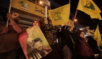 FILE - In this Oct. 25, 2019 file photo, supporters of Hezbollah leader Sayyed Hassan Nasrallah hold his pictures and waves Hezbollah flags in the southern suburb of Beirut, Lebanon. Iranian-backed Hezbollah built a reputation among supporters in Lebanon as a champion of the poor and a defender of the country against Israel&#39;s much more powerful military. Lebanon’s protests have shown unusual overt anger at the country’s powerhouse, Hezbollah. (AP Photo/Hassan Ammar, File)