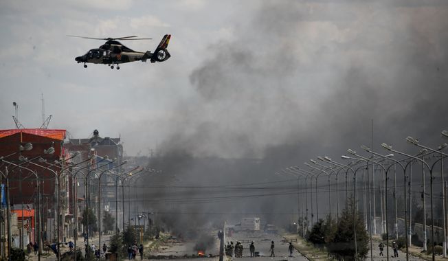 An Army helicopter flies over the road leading to the state-own Senkata filling gas plant in El Alto, on the outskirts of La Paz, Bolivia, as supporters of former President Evo Morales set up barricades, Tuesday, Nov. 19, 2019. Morales&#x27; backers have taken to the streets asking for his return since he resigned on Nov. 10 under pressure from the military after weeks of protests against him over a disputed election he claim to have won. (AP Photo/Natacha Pisarenko)