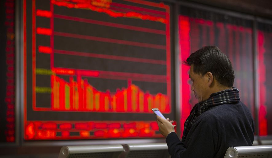 In this Tuesday, Nov. 19, 2019 photo, a Chinese investor uses a smartphone as he monitor stock prices at a brokerage house in Beijing. Shares retreated in Asia on Wednesday after Japan reported its worst monthly decline in exports in three years. (AP Photo/Mark Schiefelbein)