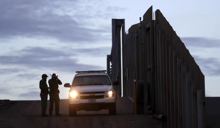 In this Wednesday, Nov. 21, 2018, photo, United States Border Patrol agents stand by a vehicle near one of the border walls separating Tijuana, Mexico, and San Diego, in San Diego. (AP Photo/Gregory Bull) ** FILE **