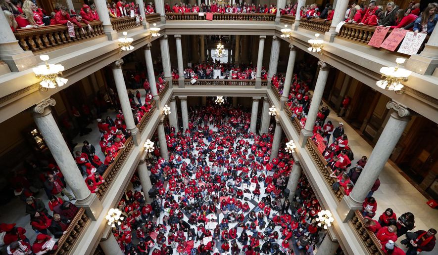 Thousands of Indiana teachers wearing red hold rally at the Statehouse in Indianapolis, Tuesday, Nov. 19, 2019, calling for further increasing teacher pay in the biggest such protest in the state amid a wave of educator activism across the country. Teacher unions says about half of Indiana's nearly 300 school districts are closed while their teachers attend Tuesday's rally while legislators gather for 2020 session organization meetings.(AP Photo/Michael Conroy)