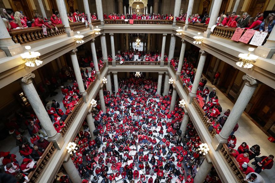 Thousands of Indiana teachers wearing red hold rally at the Statehouse in Indianapolis, Tuesday, Nov. 19, 2019, calling for further increasing teacher pay in the biggest such protest in the state amid a wave of educator activism across the country. Teacher unions says about half of Indiana's nearly 300 school districts are closed while their teachers attend Tuesday's rally while legislators gather for 2020 session organization meetings.(AP Photo/Michael Conroy)