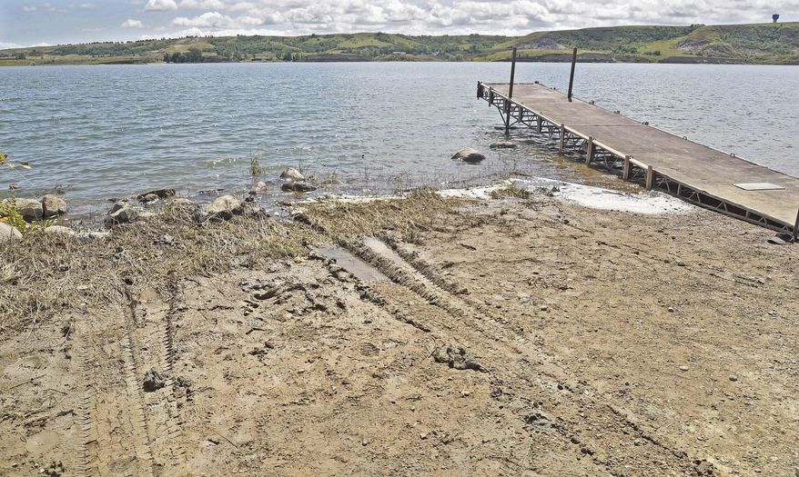 In this Aug. 1, 2018 photo, Tire tracks are visible on the shore of Sanish Bay where a pickup truck was recovered from Lake Sakakawea in North Dakota. Federal prosecutors on Wednesday, Nov. 20, 2019 released new details in the disappearance of an American Indian woman whose body was found in a submerged truck in a North Dakota lake, including an affidavit that said she was strapped into the passenger side with a seat belt around her waist. (Tom Stromme/The Bismarck Tribune via AP)