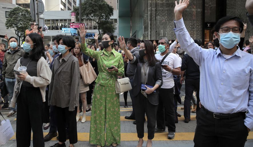 Protesters hold up their hands to symbolize pro-democracy demonstrators' five demands during a demonstration in the financial district in Hong Kong, Wednesday, Nov. 20, 2019. Hong Kong schools reopened Wednesday after a six-day shutdown but students and commuters faced transit disruptions as the last protesters remained holed up on a university campus. (AP Photo/Kin Cheung)