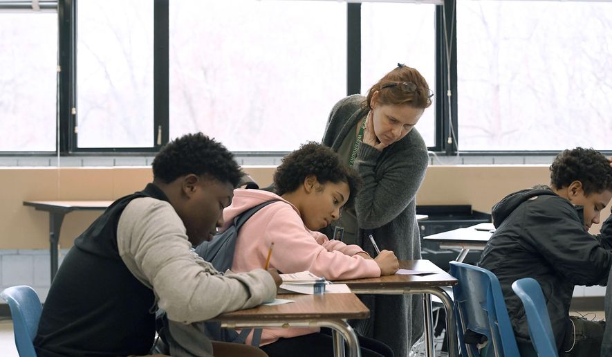 In this Nov. 7, 2019, photo, Crosby High School algebra teacher Jennifer Desiderio works with freshman students in her class in Waterbury, Conn. While students in the Waterbury public school district are predominantly black and Hispanic, the vast majority of its educators, as in school districts across the country, are white. (AP Photo/Jessica Hill)