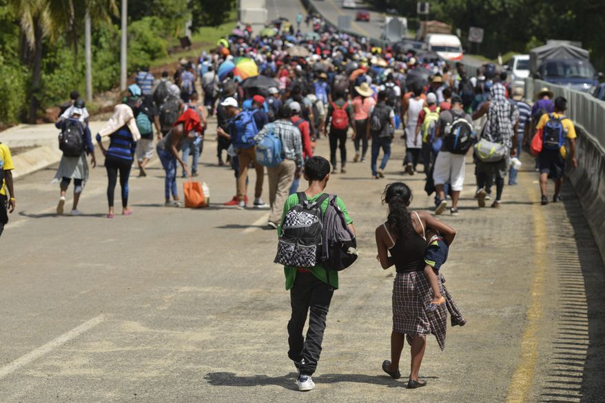 In this Oct. 12, 2019, file photo, migrants walk down Highway 200 en route to Huixtla, near Tapachula, Chiapas state, Mexico. Five American journalists brought a lawsuit Wednesday, Nov. 20, 2019, against the U.S. government that alleges border authorities violated their First Amendment rights by inspecting their cameras and notebooks and questioning them extensively about their coverage of last year's migrant caravan. (AP Photo/Isabel Mateos, File) **FILE**